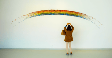 A person taking a picture of a rainbow mural
